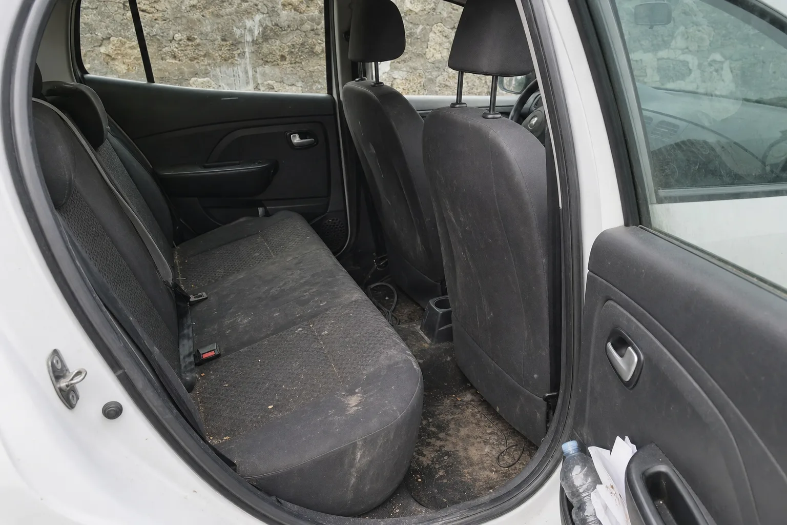 Nettoyage intérieur de voiture à domicile à Orléans — habitacle avant intervention : sièges en tissu tachés, tapis maculés, déchets au sol.