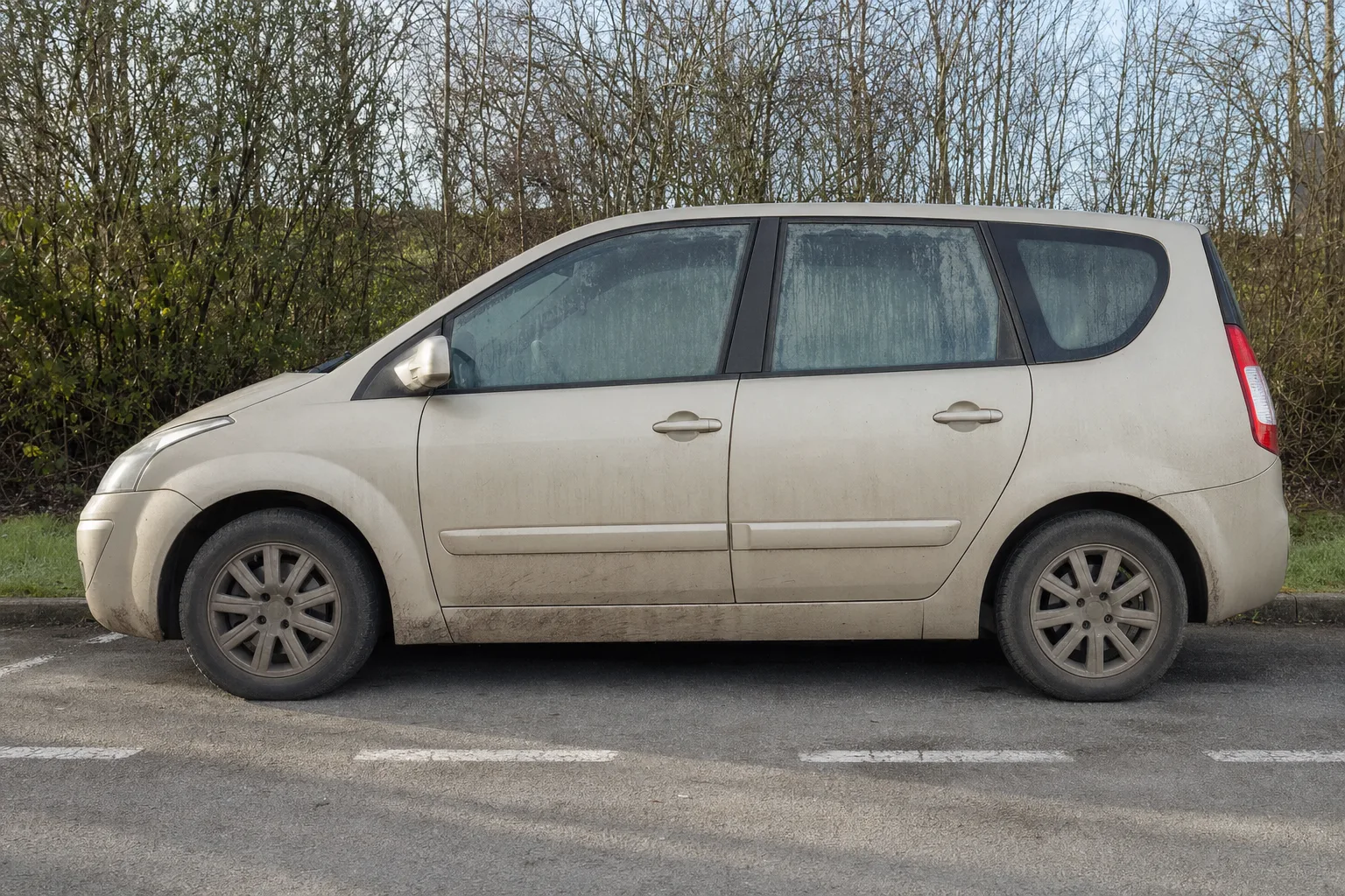 Lavage extérieur de voiture à domicile à Lille — flanc avant intervention : carrosserie poussiéreuse, bas de caisse sale, jante noircie.