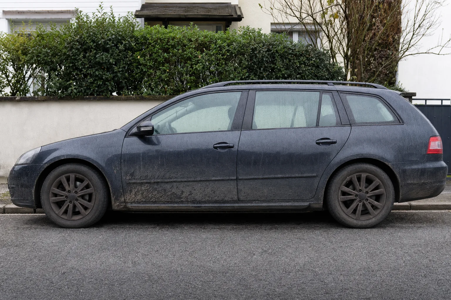 Lavage extérieur de voiture à domicile à Lyon — flanc avant intervention : carrosserie poussiéreuse, bas de caisse sale, jante noircie.