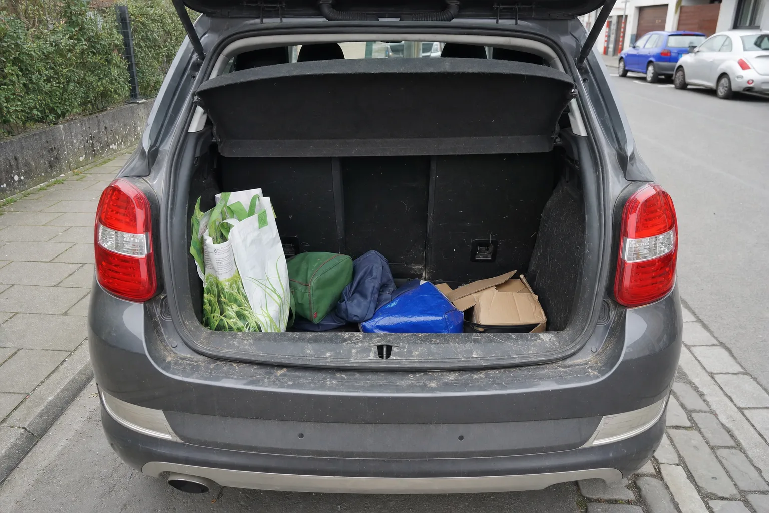 Remise en état de coffre à domicile dans le Val-de-Marne — coffre avant intervention : moquette tachée, poils et sable incrustés, objets en désordre.