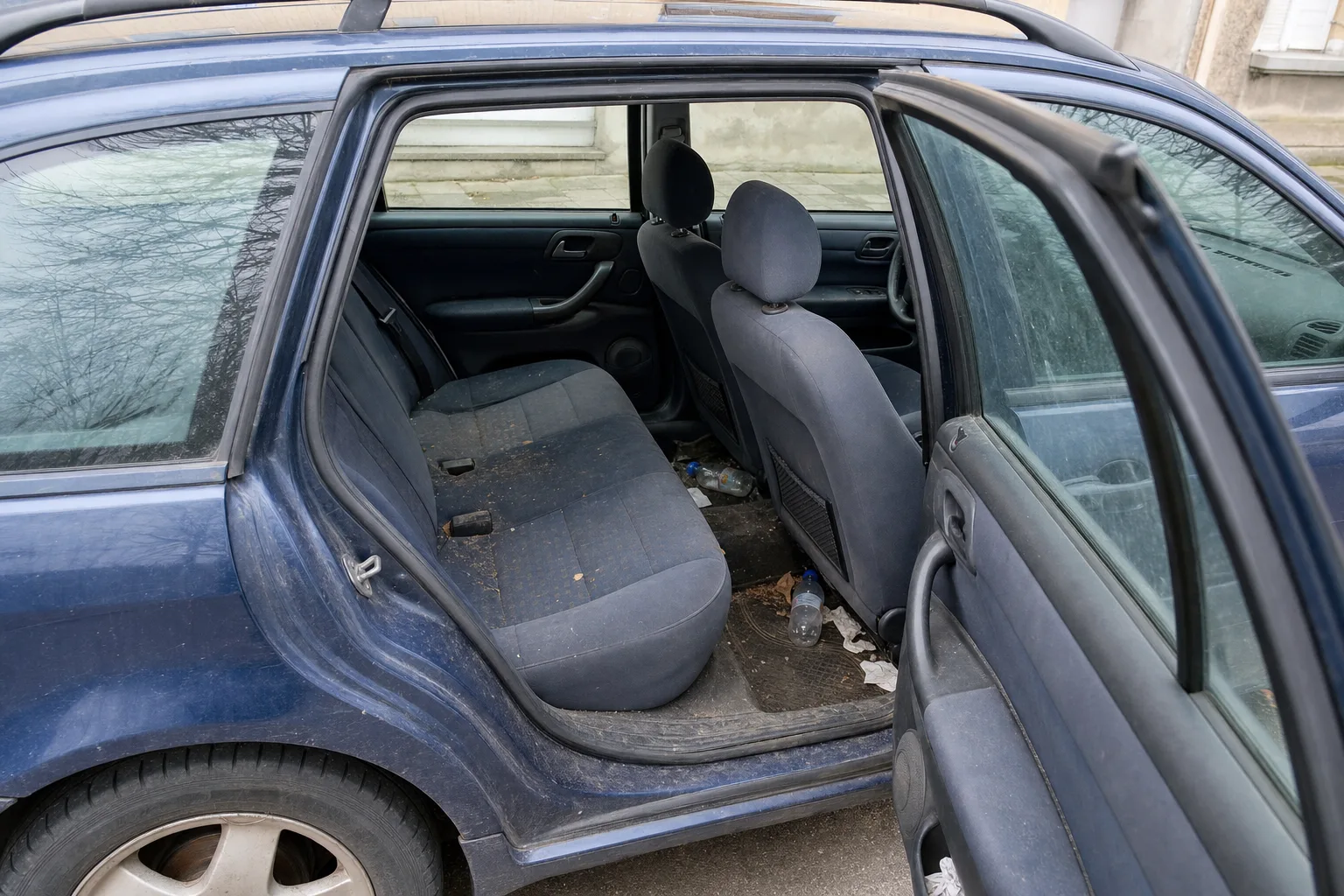 Nettoyage intérieur de voiture à domicile dans le Val-de-Marne — habitacle avant intervention : sièges en tissu tachés, tapis maculés, déchets au sol.